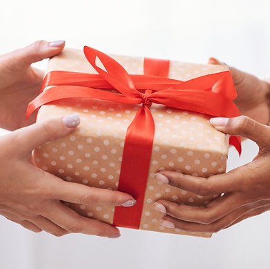 Holiday Celebration Concept Closeup on female hands holding gift with red bow and giving p