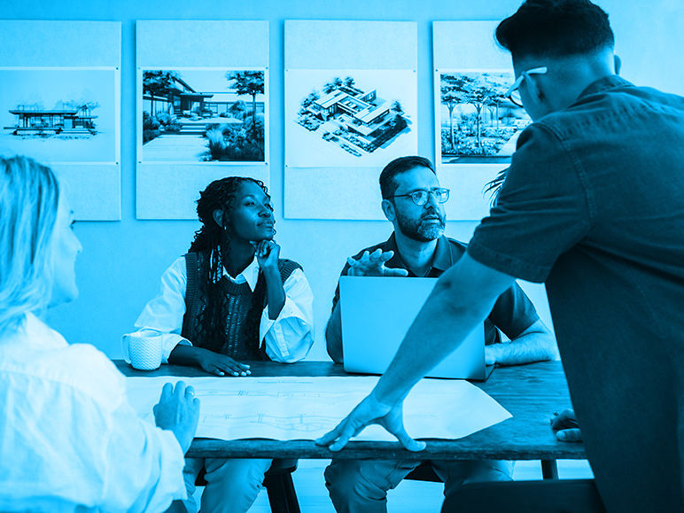 AEC project team collaborating around drawings and a laptop during a strategic teaming partnership meeting