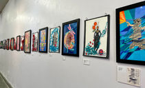 Gallery wall displays framed artworks, ARTISANRY, VISUAL ARTS, PAINTING on plaques.