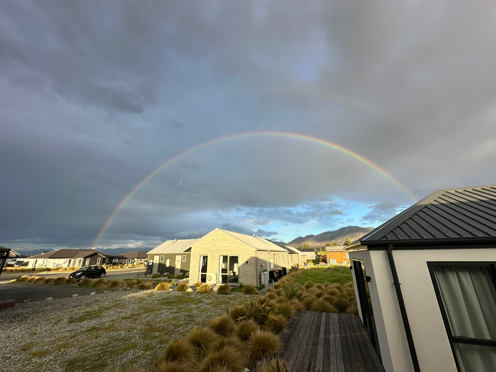 A Double Rainbow Over Lake Tekapo A shot of a double rainbow over the neighborhood in Lake Tekapo, New Zealand just around sunset with dark storm clouds in the sky