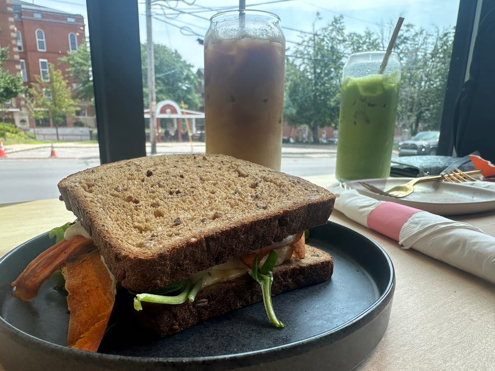 Vegan breakfast sandwich and iced latte with street behind glass window
