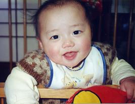 赤ちゃんがよだれを垂らしてニコニコしながらこっちを向いている写真