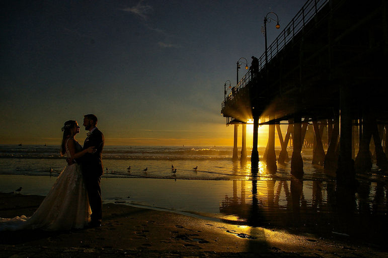 Couple de jeunes mariés au couché du soleil sur une plage de Bretagne