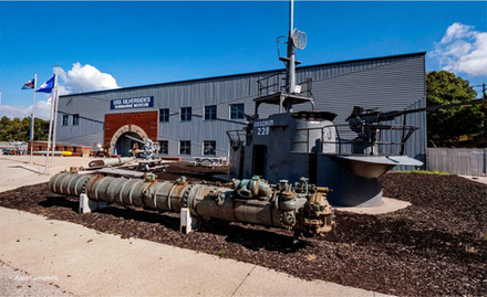 Exterior view of two-story Submarine Museum with parts from submarine in front.