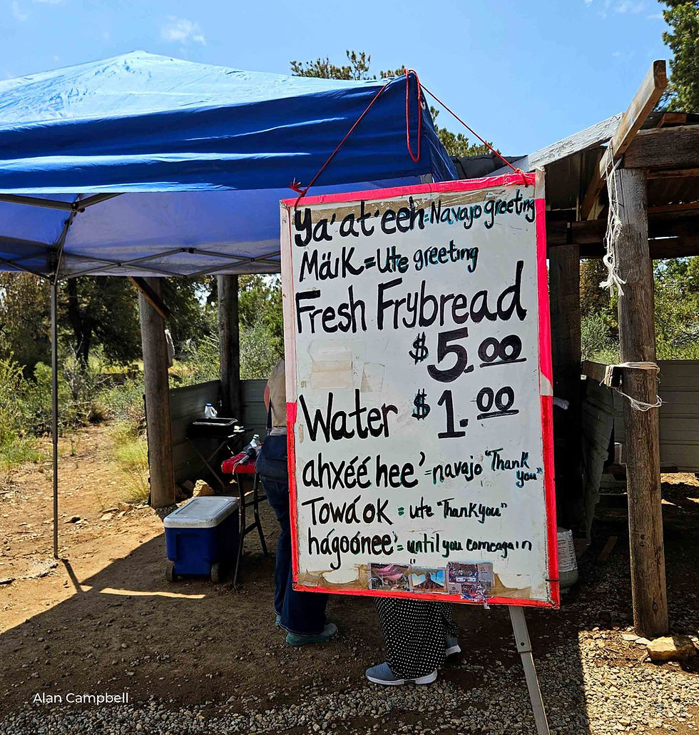 Sign advertising Fresh Frybread for $5 and water for $1. Navajo greeting says ya'at.eeh. Ute greeting reads Maik