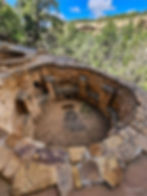 Kiva in cliff dwellings is similar to a basement without a roof. Round structure with rocks stacked to form walls and a firepit in center.