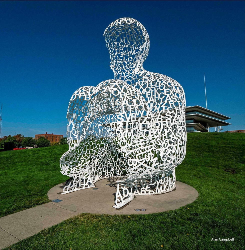 Photo of large white sculpture of letters that looks like a sitting person.