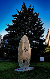 Outdoor sculpture that looks like a large stone egg with a coat of arms carved in the top