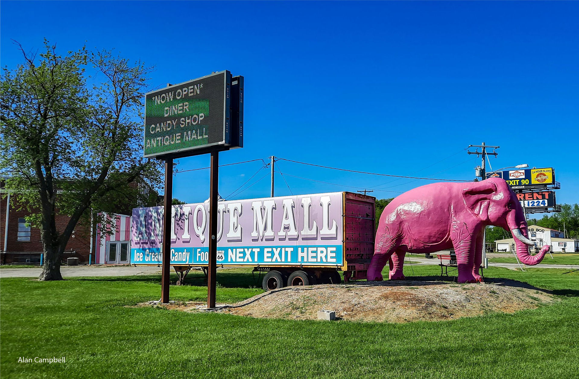 Photo of large pink elephant with a semi-truck trailer behind reading Antique Mall