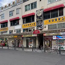 Exterior of the Akihabara Radio Kaikan-area building housing Maid Cafe Granvania, with its illustrated maid cafe sign displayed above the street-level shops.