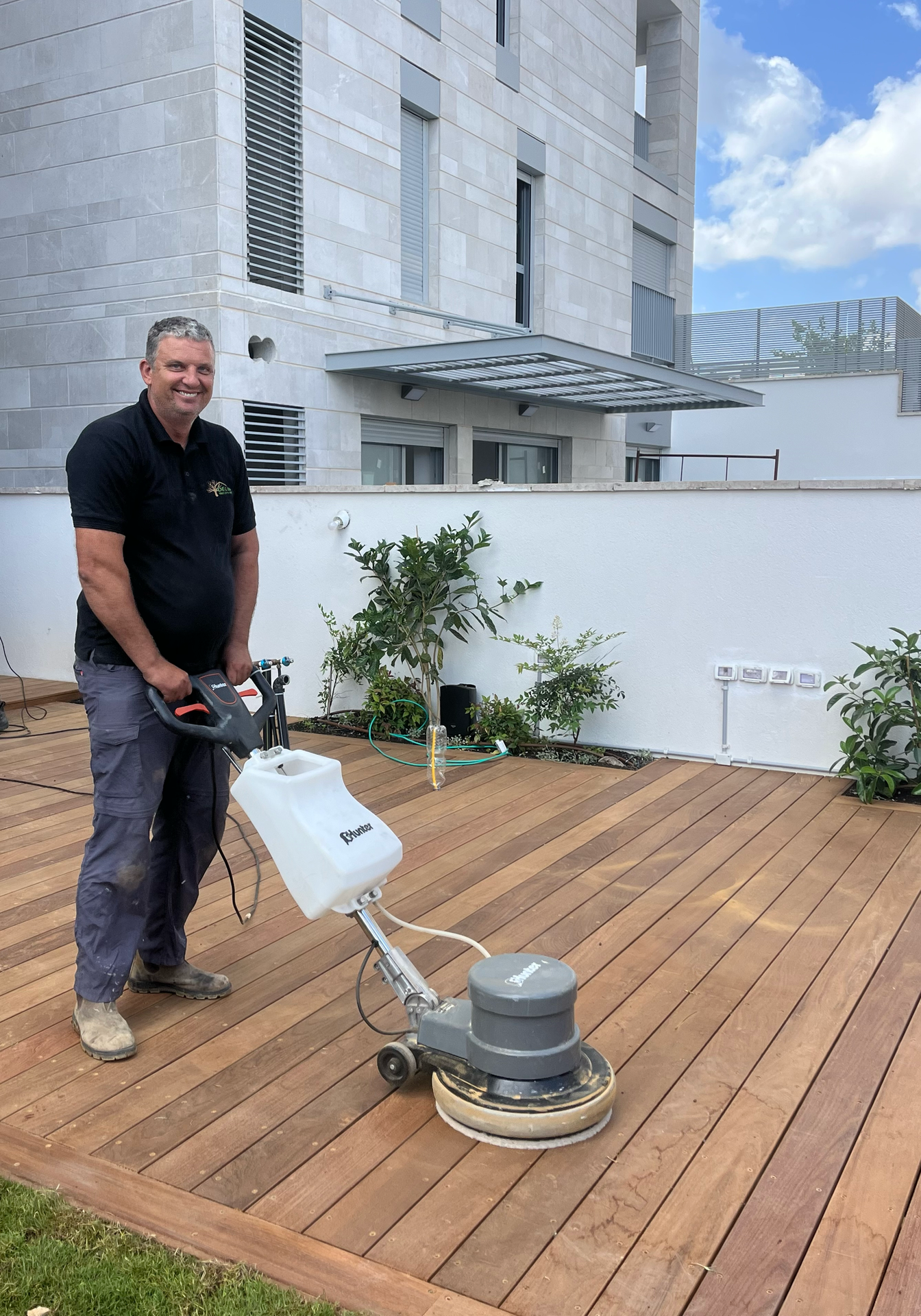 Smiling man cleaning a deck with a power washer