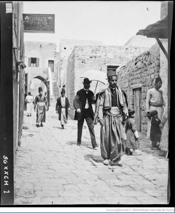 Men in traditional clothing walking down a narrow street