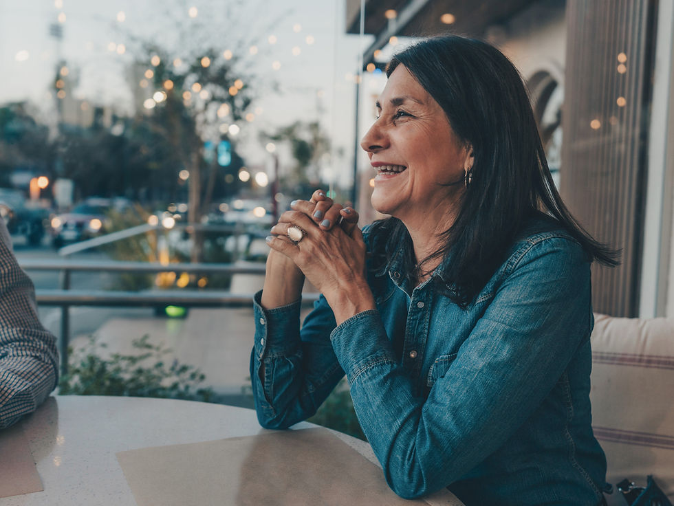An older woman sitting at a table, smiling.