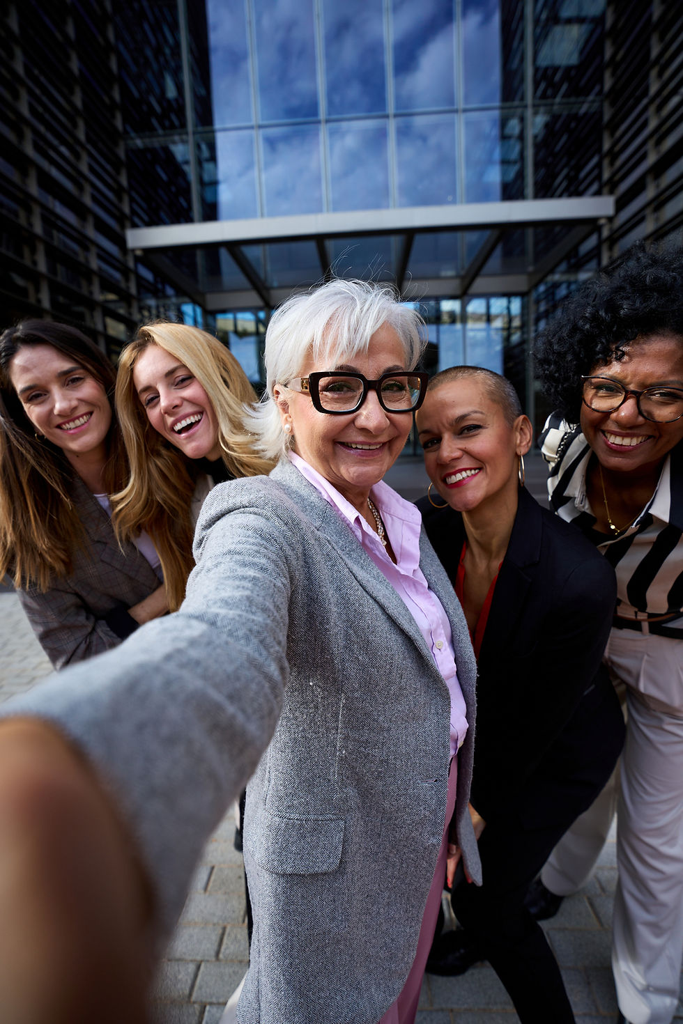 A group of women smiling, taking a selfie.