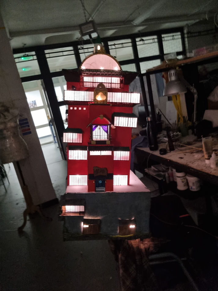 the model of the bathhouse in a dark room, with the windows lit up.