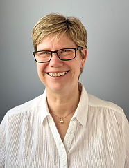 Sue is a white woman in her mid 50's, she has short blonde hair and is wearing glasses and a white button up collared shirt.