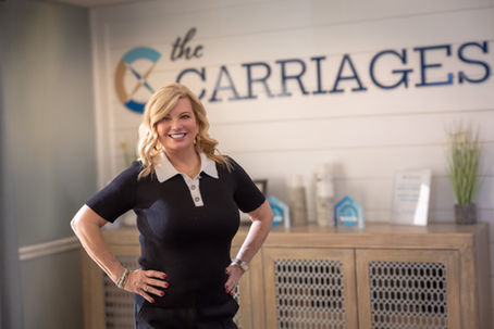 Carrie Boone, Founder and CEO of Generation Healthcare Managers, smiling in front of The Carriages signage.