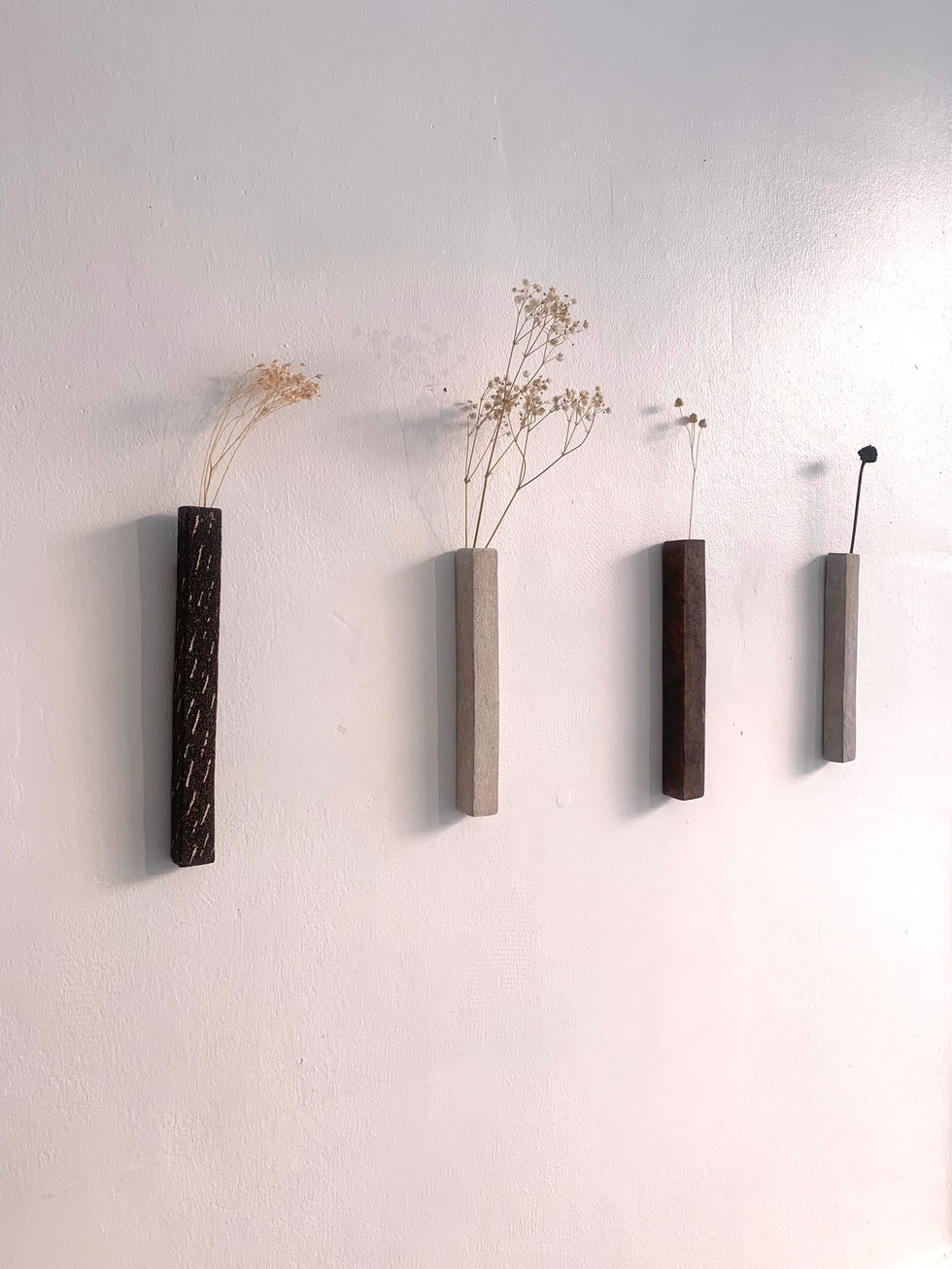 Soliflores rectangulaires en céramique, accrochés au mur et contenant des fleurs.