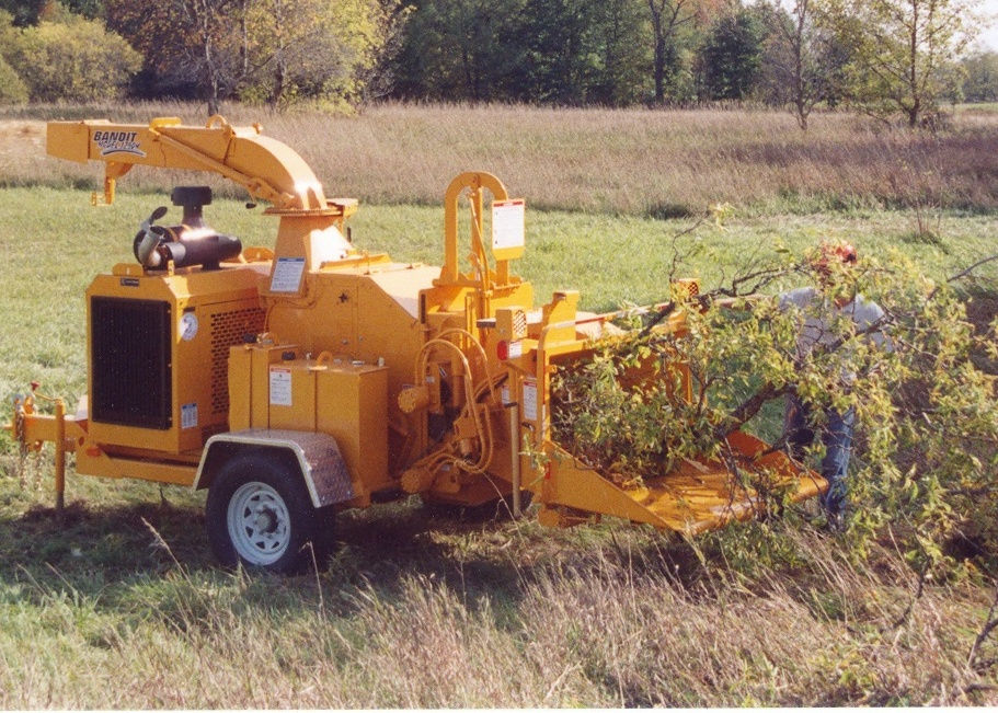 Branches being feed into a large yellow wood chipper