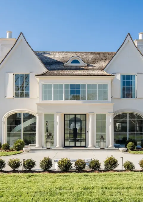 Custom-built home with dramatic cast stone column entry, ornate double doors, and turret-style stonework