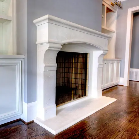 Elegant white fireplace surround with classical architectural details, complementing a modern living room with wooden floors