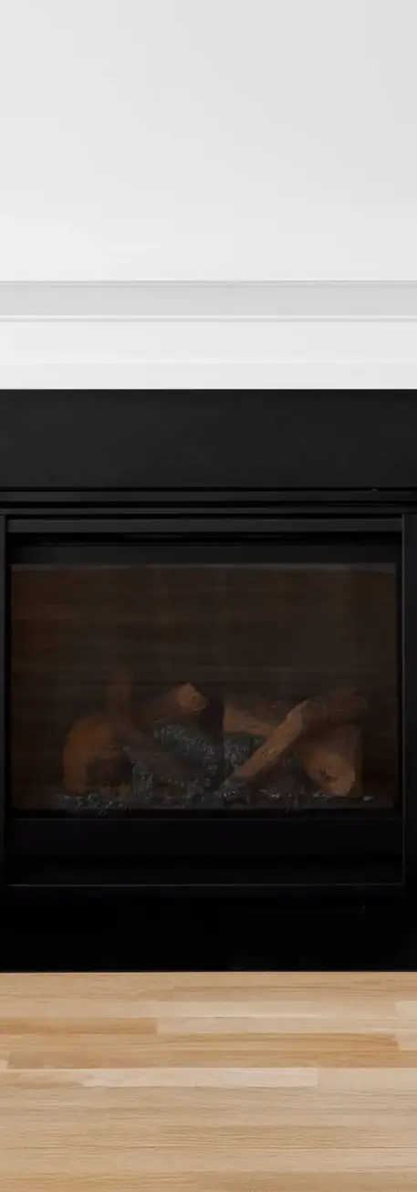 Sleek and modern fireplace surround with a black and white color scheme highlights a cozy hearth, framed by elegant cabinetry