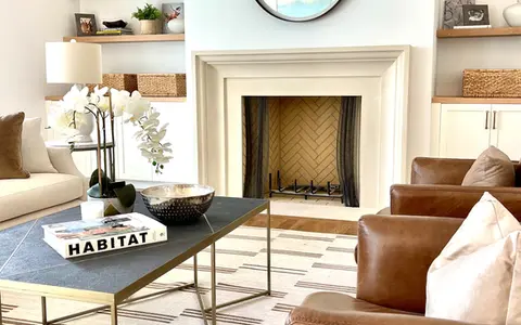 A stylish living room with a limestone fireplace seamlessly integrated into chic decor, featuring neutral tones.