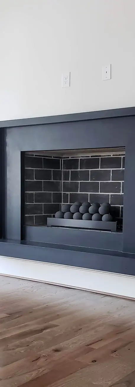 Modern and sleek fireplace surround featuring a dark, minimalist design, complemented by a gray brick interior.