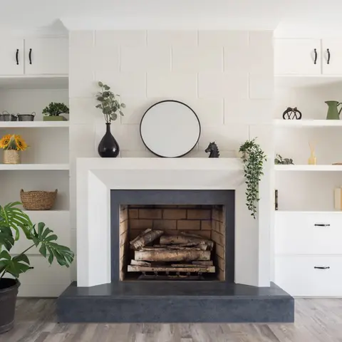 Elegant stone fireplace surround with minimalist decor and lush greenery.