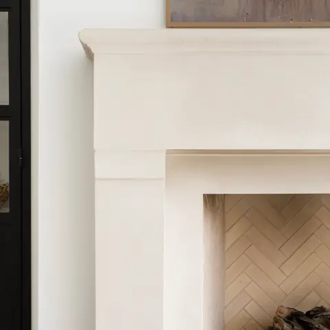 Elegant fireplace mantel showcasing clean lines and a smooth, minimalist design, complemented by herringbone brickwork inside