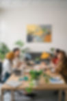 Four women sitting around a table, engaging in conversation, representing the supportive community of the Nourished Women’s Circle.