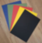 Fünf bunte Blätter Papier in Blau, Grün, Rot, Gelb, Schwarz.