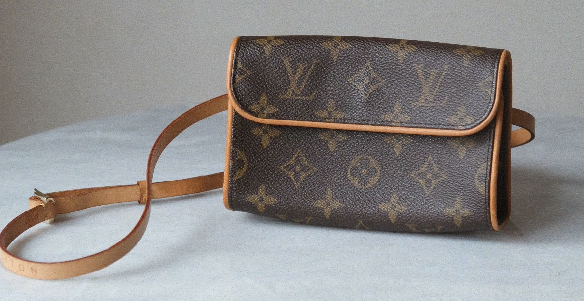 Louis Vuitton-skulderveske med monogram og patinert skinnrem på et bord.