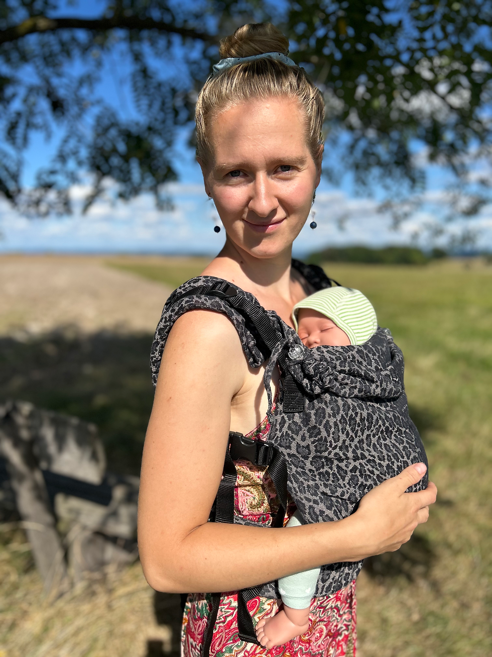 Mama trägt ihr Baby in einer komfortablen Fullbuckle-Babytrage nah am Herzen