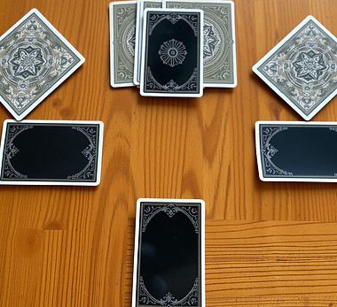 Oracle cards with an ornate backing forming a square on a wooden table.jpg