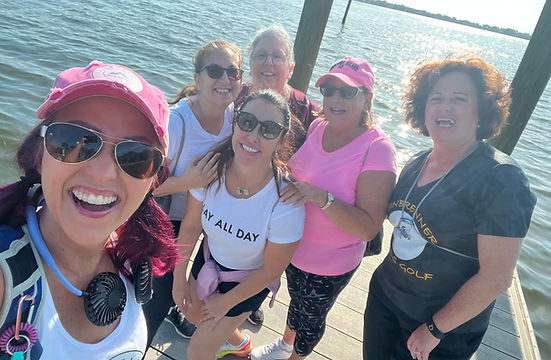A group of smiling happy women with backpacks standing on a dok on the water