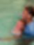 swim instructor smiling in pool holding toddler swimmer