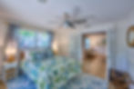 Cozy queen bedroom with floral decor and direct access to a private patio, offering a tranquil retreat.
