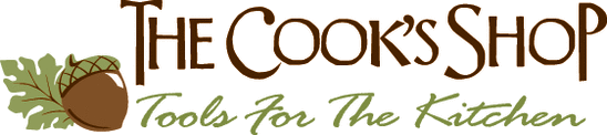 This is the logo for The Cook's Shop. Besides the business name is a tag line: Tools For The Kitchen, and the businesses logo, and acorn and oak leaf.