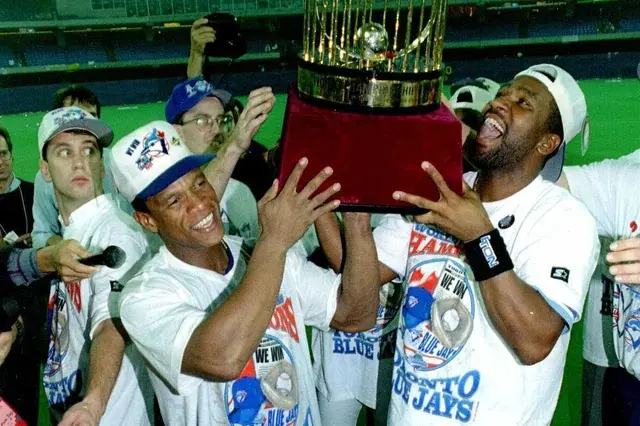 Rickey Henderon and Joe Carter lifting the World Series trophy after Carter's walk-off home run in game 6.