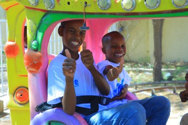 Photo of two orphans enjoying a ride at the Global Orphan Eid Party. 