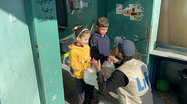 Photo of LIFE team member giving a young girl and her brother hot meals.  