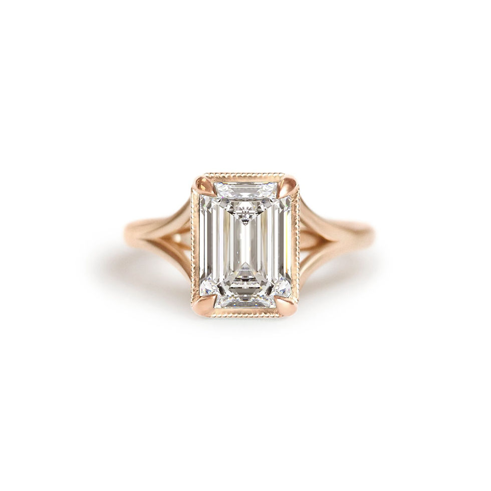 An emerald cut diamond solitaire ring with a rose gold band and milgrain detailing.