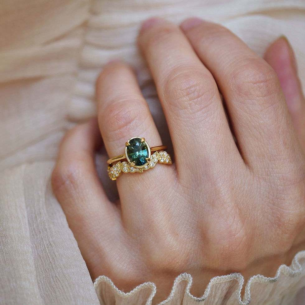 Thumbnail: Close-up of a hand wearing a nature inspired gold band with a green sapphire engagement ring.