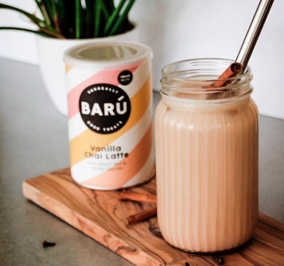 Pot met poeder om zelf vanilla chai latte te maken en een gemaakte chai latte ernaast in een leuk glas met een rietje