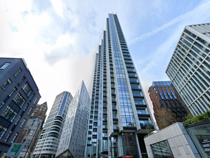 Skyscraper with glass facade surrounded by modern buildings under a blue sky. Cityscape with a mix of architectural styles.