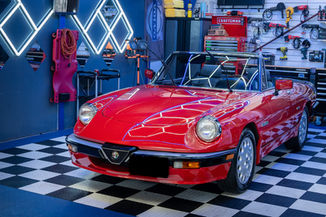 Vintage red Alfa Romeo Spider with ceramic coating protection in a professional studio.