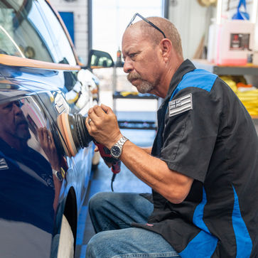 Close-up of a Gloss Masters detailer using a dual-action polisher to restore paint clarity on a customer's vehicle.