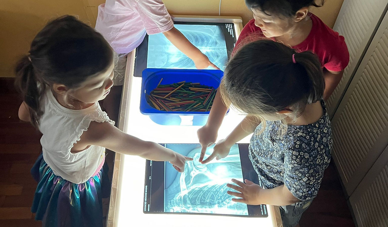 Children pointing at bones from an xray image on top of a light box
