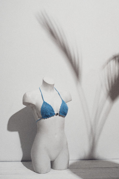 white female statue with knitted bikini on white floor 